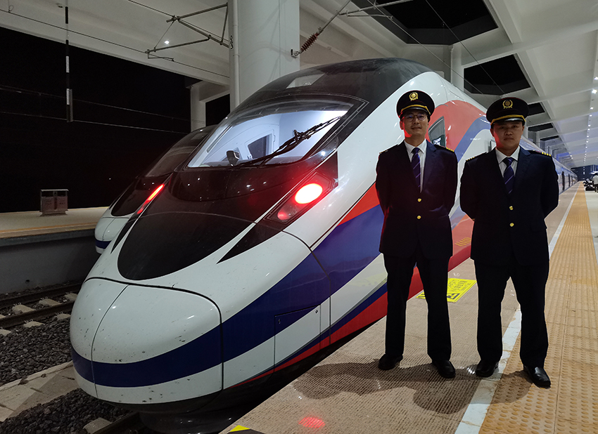 劉銀能（右一）與中國師父鄔俊鴻在動車組前合影。受訪者供圖